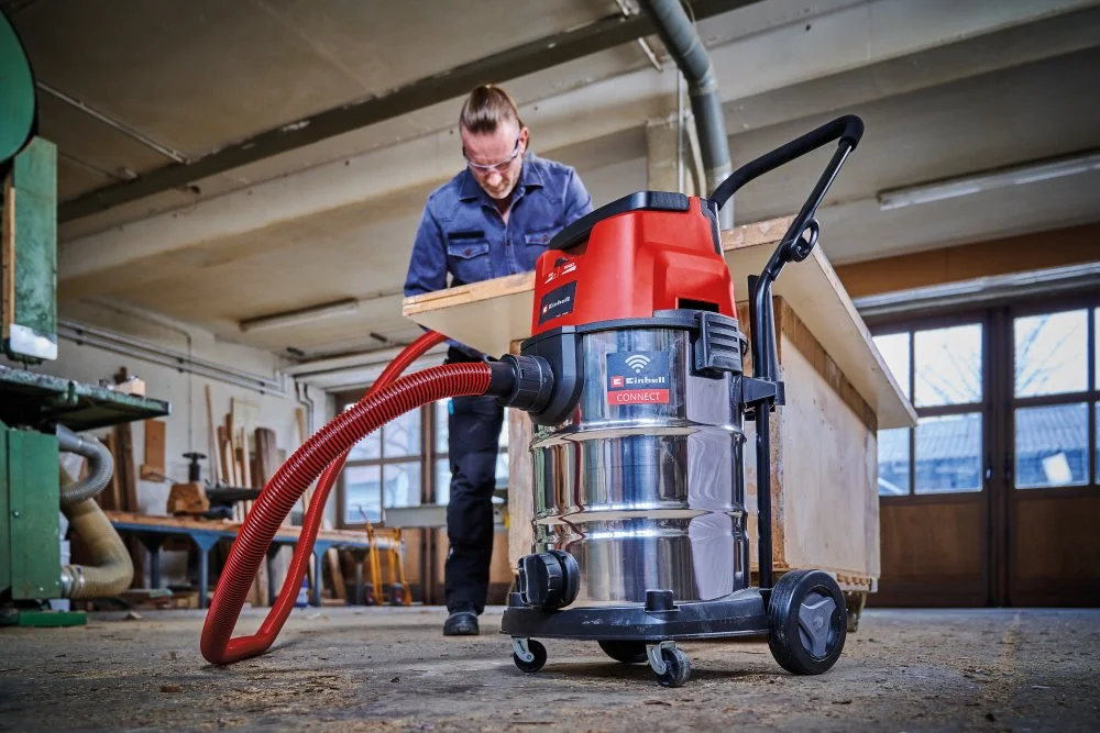 Person verwendet einen Nass- und Trockensauger in einer Werkstatt.